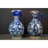 Pair of Persian Glazed Jugs with pinched spouts decorated with foliage in shades of blue, 25cms high