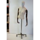 Female Shop Mannequin with articulated wooden arms, cloth body and raised on a metal industrial