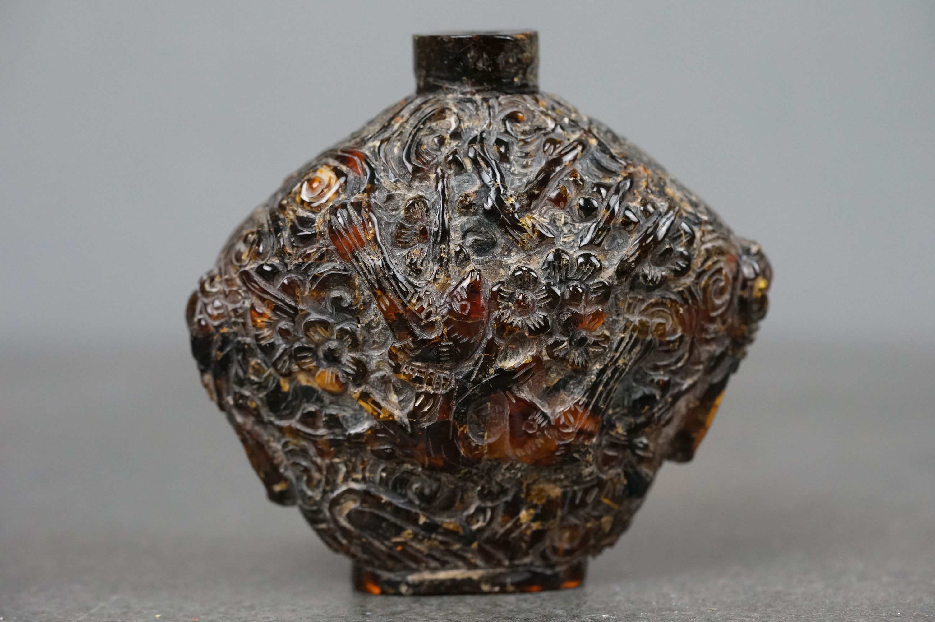 A Chinese finely carved amber snuff bottle with decorative birds to front and rear.