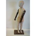Child Shop Mannequin with articulated wooden arms, cloth body and stood on a wooden base, 113cms