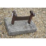 A vintage wrought iron boot scraper set into a stone block.