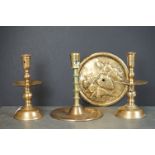 A pair of antique brass candlesticks together with two further candlesticks and a brass plaque.