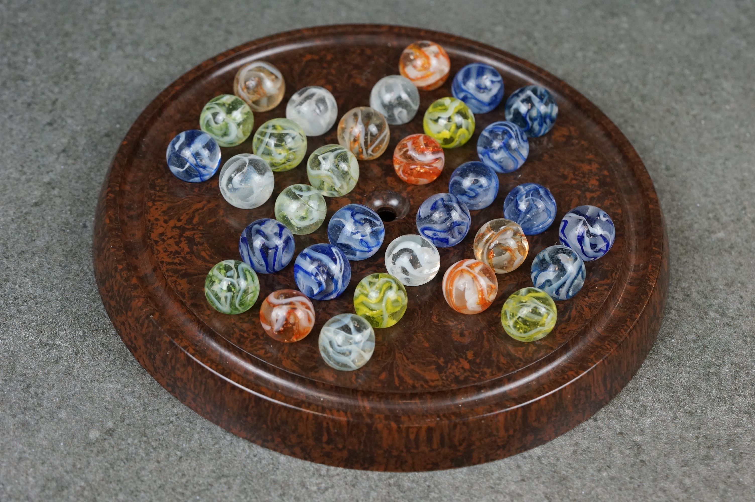 A vintage game of solitaire with bakelite board and vintage marbles.