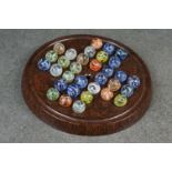 A vintage game of solitaire with bakelite board and vintage marbles.