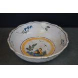 A vintage tin glaze bowl with central scene and floral surround.