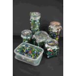 A large collection of mixed marbles contained within six containers.