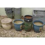 A collection of five decorative outdoor ceramic planters together with a stone example.