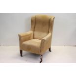 Early 20th century Upholstered Wing Back Armchair raised on square tapering legs with castors, 74cms