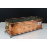 A copper flower trough with lion head handles and feet.