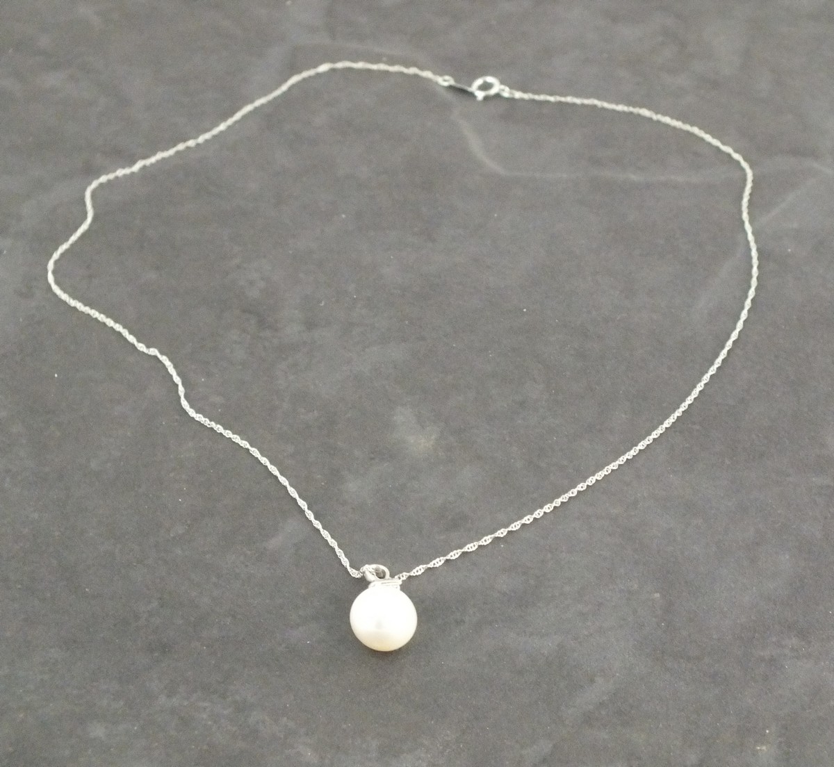 A pearl and diamond drop necklace, the peal with a 9ct white gold bail set with three diamonds, on a