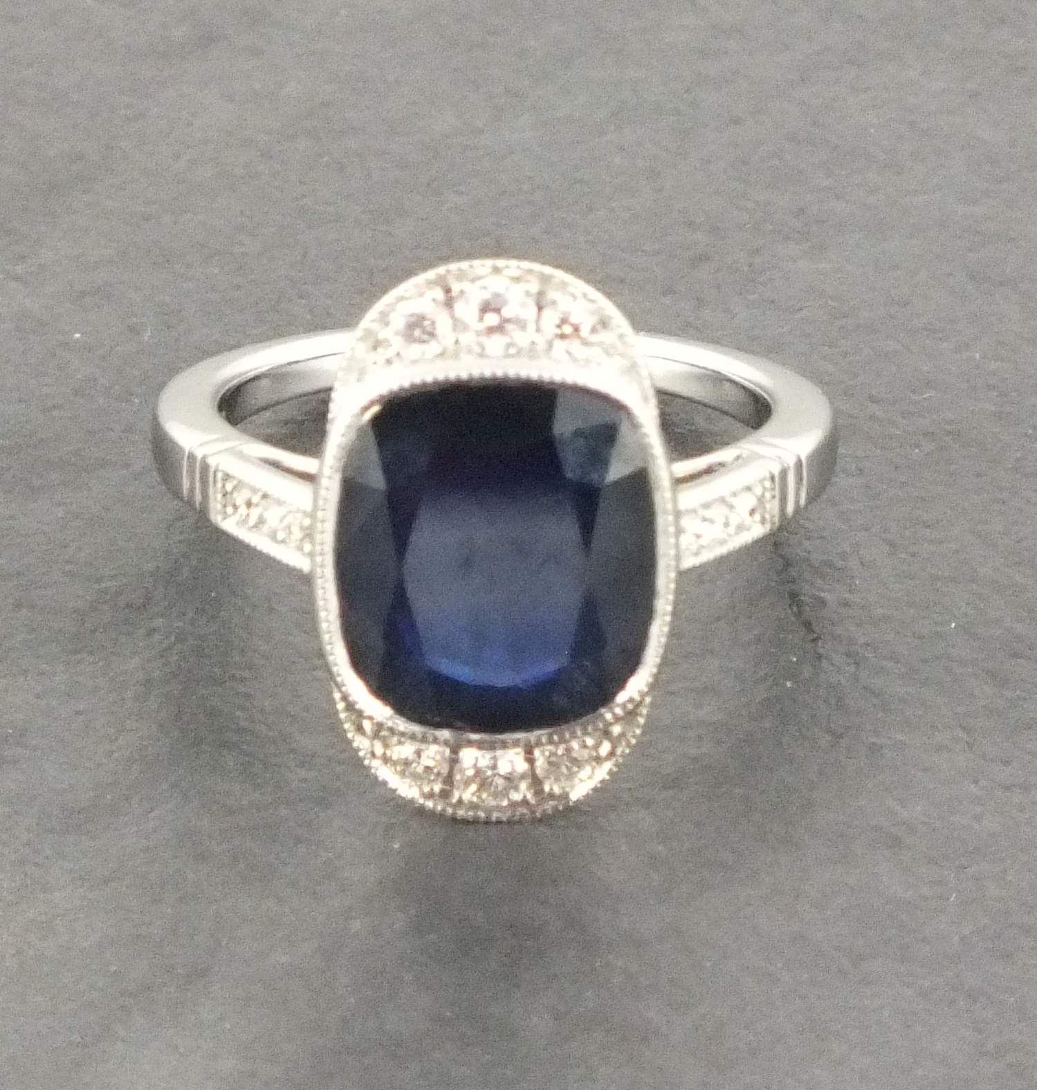 An 18ct white gold cushion sapphire and diamond art deco style cluster ring with diamond