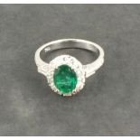 An emerald and diamond dress ring, the oval cut central stone approx. 1.68ct within a border of