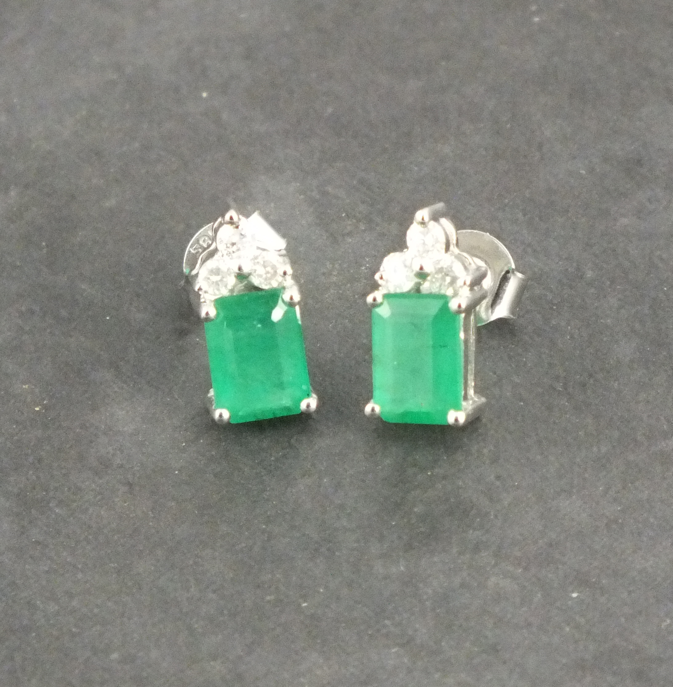 A pair of emerald and diamond set ear pendants, the rectangular cut stones with three cluster