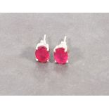 A pair of ruby ear studs, the oval treated stones claw set within silver