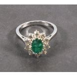 A emerald and diamond dress ring, the oval central stone within a border of diamonds, set in 18ct