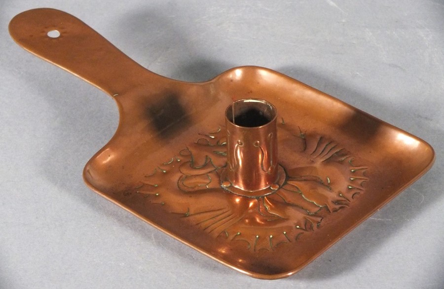 A late 19th Copper chamberstick, possibly Newlyn, of square paddle form, repousse decorated with