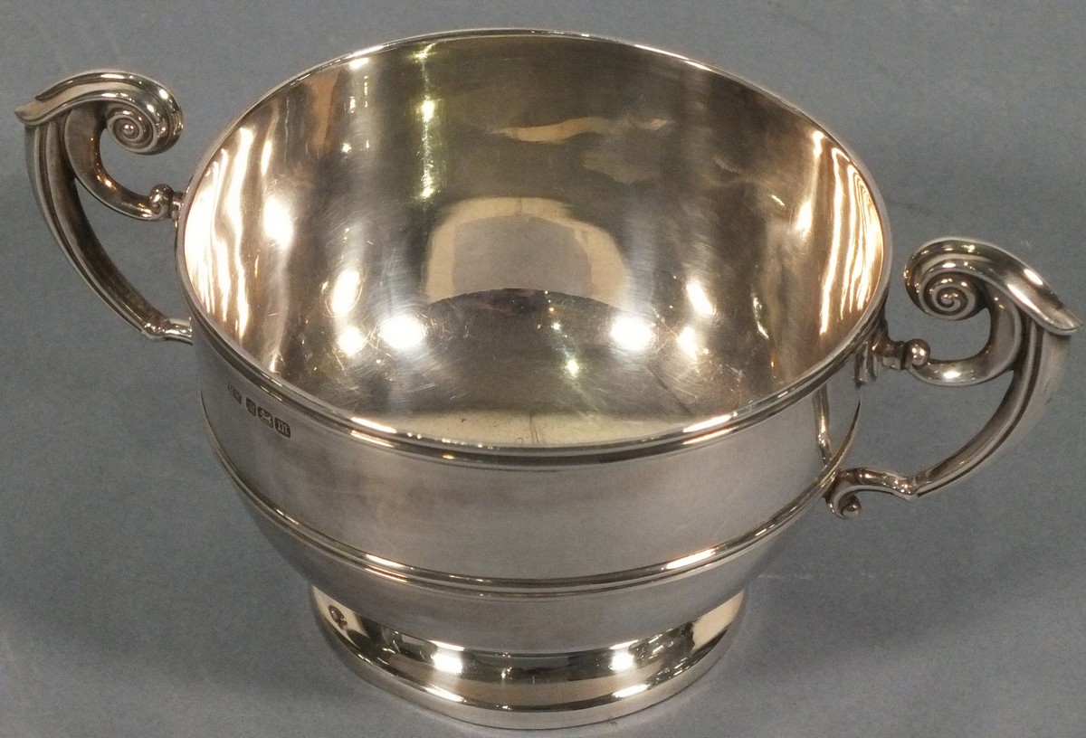 A silver twin handle cup, Sheffield 1904, Henry Wigfull, with a reeded girdle and raised on a