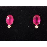 A pair of ruby and diamond ear studs, claw set in 18ct yellow gold, the oval stones with a diamond