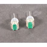 A pair of emerald and diamond cluster ear studs, the rectangular central stones within a band of