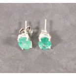 A pair of emerald ear studs, oval cut claw set in silver