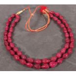 A red bead two strand necklace, of pear-shaped carved stones, on an adjustable cord, approx. 1034.