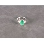 An emerald and diamond ring, the central oval stone approx. 4.45ct flanked by trillion cut stones