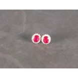 A pair of ruby and diamond ear studs, the oval rubies glass filled, set within a band of diamonds,