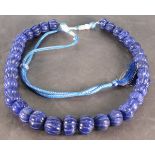 A string of blue beads, the graduated carved round beads, on an adjustable cord.