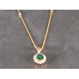 An emerald and diamond cluster pendant, the oval central stone set within a band of diamonds in