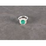 An emerald and diamond set dress ring, the emerald cut central stone approx. 3.44ct, set in 18ct