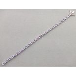 A tanzanite and diamond line bracelet, the oval tanzanite stones cla set between pairs of