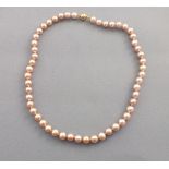 A string of pink freshwater cultured pearls, set with a 9ct gold ball clasp, 44cm long