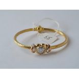 A BANGLE WITH HEART SHAPED DIAMOND CENTRE PIECE IN 9CT