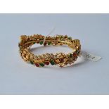 An attractibe yellow metal bracelet encrusted with pearl, emerald & ruby style stones in swirls &