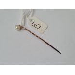 A real single pearl set stick pin in high carat gold
