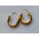 A pair of yellow metal hooped earrings