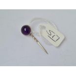 A small silver stick pin set with a cabochon amethyst