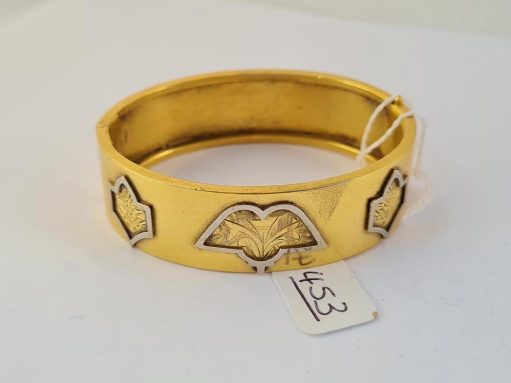 A wide gilt metal bracelet - marked E Atkins patent with 3 floral design to front