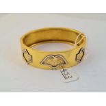 A wide gilt metal bracelet - marked E Atkins patent with 3 floral design to front
