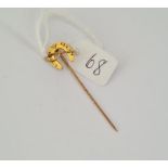 An antique hunting stick pin designed as horse shoe with riding crop in gold