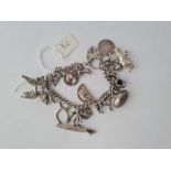 A silver charm bracelet set with numerous charms inc a Poodle charm 55g