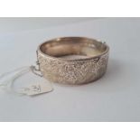 A wide hinged scroll engraved silver bangle