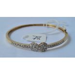 An attractive 9ct hinged bangle set with CZ ribbon bow design 8.4g inc