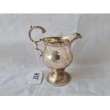A George III helmet shaped cream jug with gadroon rims and leaf capped handle - 4.5" high - London