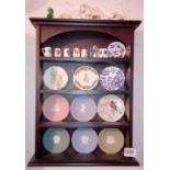 A shelf with 3" wedgwood plates, thimbles etc