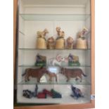 A glazed cabinet with various cows, milk maid etc