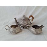 An Indian three piece tea set with chased decoration and elephant finial - 7.5" wide - 874 g.