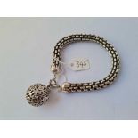 A large white metal woven bracelet with ball design clasp