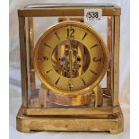 An Atlas brass mantel clock by LE COULTRE with circular dial. (Glass panel to top broken). 9.5"