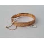 A SCROLL ENGRAVED 9CT HINGED BANGLE 15.8g